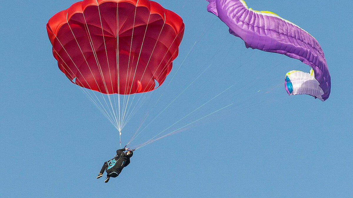 Un paracadute di emergenza aperto accanto a una vela da parapendio instabile